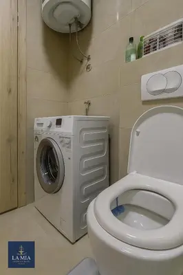 a bathroom with a toilet and a washing machine at La Mia Premium Suite in Tuzla