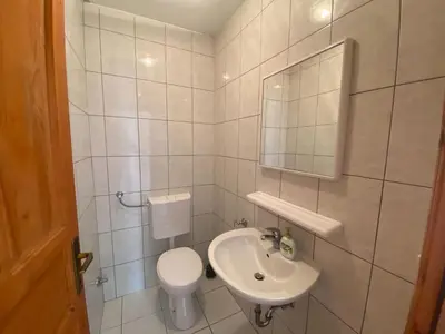 a white bathroom with a toilet and a sink at Pansion Tomas Kupres in Kupres