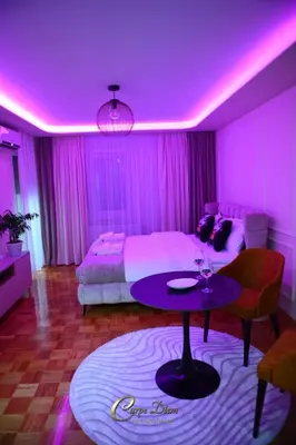 a room with a bed and a table with a purple ceiling at Carpe Diem Spa Apartman in Teslić