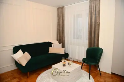 a living room with a green couch and a chair at Carpe Diem Spa Apartman in Teslić
