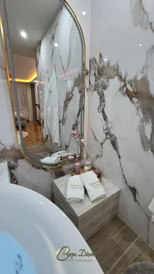a bathroom with a tub and a large mirror at Carpe Diem Spa Apartman in Teslić