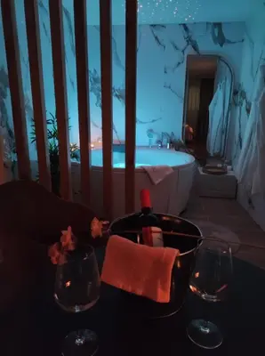 a bathroom with a tub and a sink with wine glasses at Carpe Diem Spa Apartman in Teslić