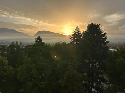 a sunset over a city with trees in the foreground at Stan na dan Kalin in Bugojno