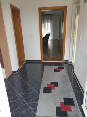 a hallway with a tile floor with a door and a rug at Villa Big Mama in Živinice