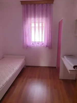 a bedroom with a bed and a window with pink curtains at Villa Big Mama in Živinice