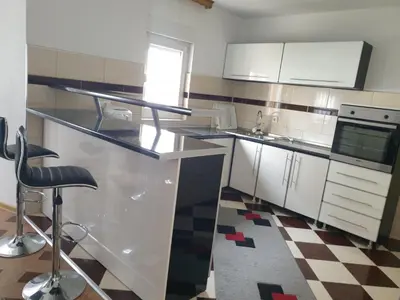 a kitchen with a counter with a sink and a stool at Villa Big Mama in Živinice