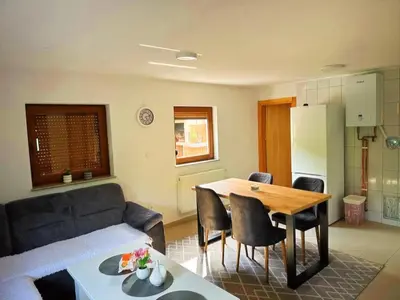 a kitchen and a living room with a table and a couch at Vikendica sa bazenom Cazin Pecigrad in Cazin