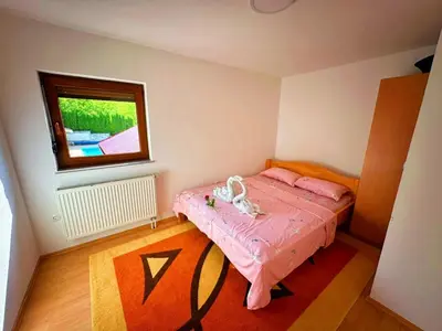 a small bedroom with a pink bed and a window at Vikendica sa bazenom Cazin Pecigrad in Cazin
