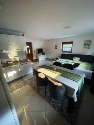 a kitchen and living room with a table and a couch at Vikendica sa bazenom Cazin Pecigrad in Cazin