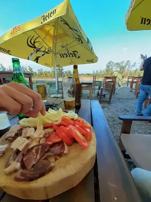 a cutting board with meat and vegetables on a table at Apartman Čeliković in Bosanski Šamac