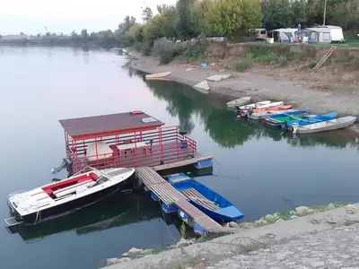 a group of boats docked at a dock on a river at Apartman Čeliković in Bosanski Šamac