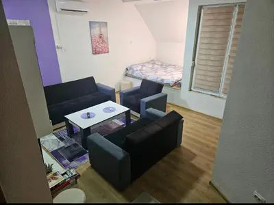 a living room with a couch and a table and a bed at Lira Apartmani in Prnjavor