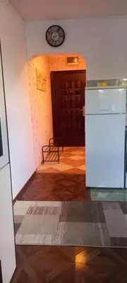 a kitchen with a refrigerator and a clock on the wall at Apartman Jelena Lux in Doboj