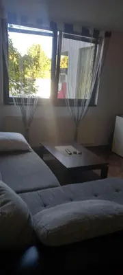a room with two beds and a table and a window at Apartman Jelena Lux in Doboj