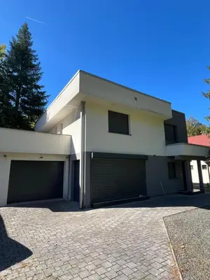 a white house with two garage doors on a driveway at Villa Bukvic in Zavidovići