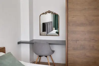 a bedroom with a chair and a mirror at Hari Apartmani Oaza in Tuzla