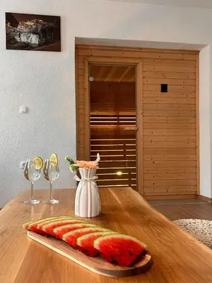 a slice of watermelon on a wooden table with wine glasses at Vikendica VIA - Čajuša, Kupres in Kupres