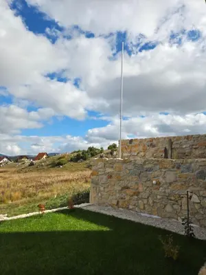 a stone wall with a flag pole in a field at Vikendica VIA - Čajuša, Kupres in Kupres