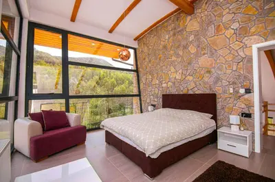 a bedroom with a bed and a stone wall at Golf Forest Creek Villas in Zavidovići