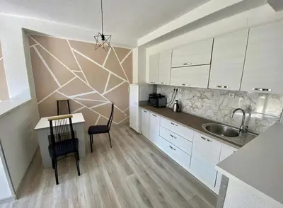 a kitchen with white cabinets and a table and a sink at Villa Lilak in Bihać