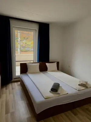 a bedroom with a large bed with a window at 3D Caffe Apartmani in Visoko