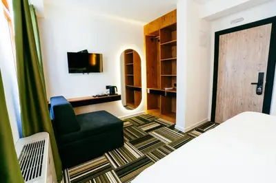 a bedroom with a bed and a chair and a television at PARK INN, Bugojno in Bugojno