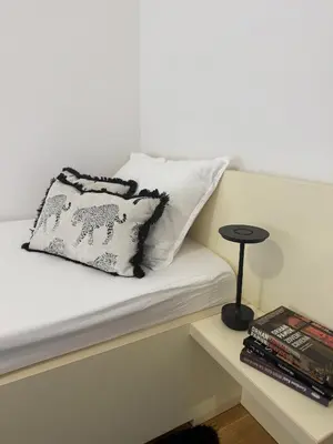 a bed with a pillow and a table with books at Urban Suite BL Apartment in Banja Luka