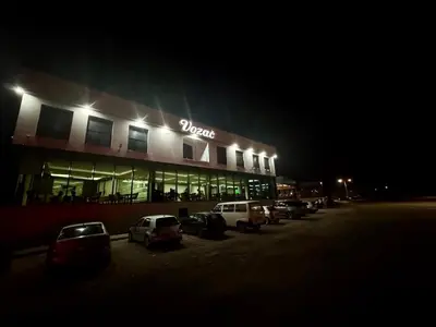 a building with cars parked in a parking lot at night at Prenoćište Vozač in Jajce