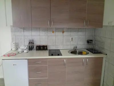 a kitchen with wooden cabinets and a sink at Apartman Mali kutak in Gradačac