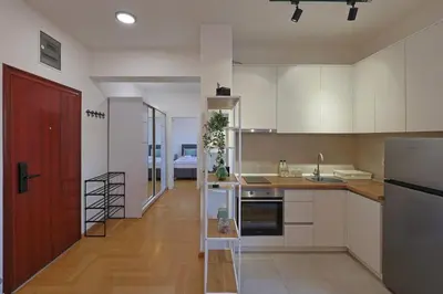 a kitchen with white cabinets and a red door at Kosta Boutique Apartment in Banja Luka