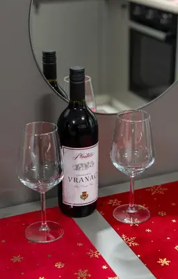 a bottle of wine and two wine glasses on a table at Apartman Elite Stay Doboj in Doboj