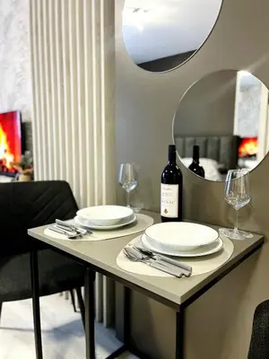 a table with plates and wine glasses and a mirror at Apartman Elite Stay Doboj in Doboj