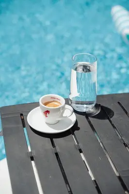 a cup of coffee sitting on a table next to a glass of water at Villa Bagrem - Villa with private pool in nature in Banja Luka