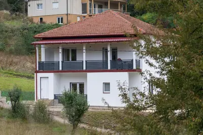a white house with a red roof on a hill at NolE Apartments in Visoko