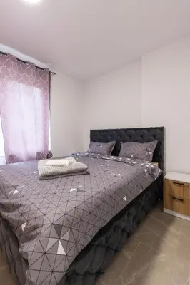 a bedroom with a bed with a purple comforter at NolE Apartments in Visoko