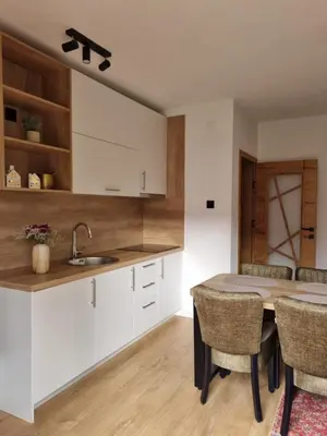 a kitchen with white cabinets and a table with chairs at Semic apartments in Visoko