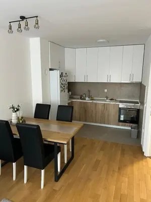 a kitchen with a wooden table and black chairs at Moonlight Apartment in Banja Luka