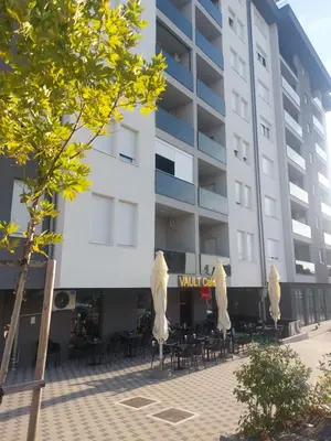 a building with chairs and umbrellas in front of it at Moonlight Apartment in Banja Luka