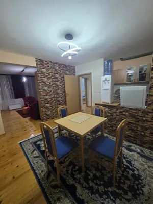 a dining room with a table and chairs and a kitchen at Vila Emani in Visoko