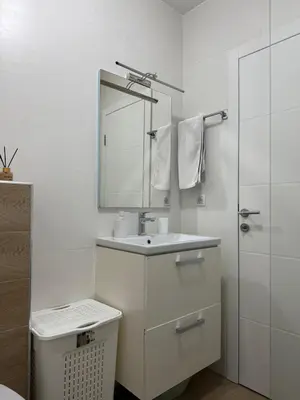 a white bathroom with a sink and a mirror at Kutak mira in Doboj