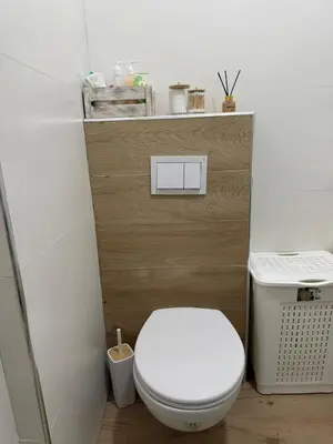 a bathroom with a white toilet with a wooden wall at Kutak mira in Doboj