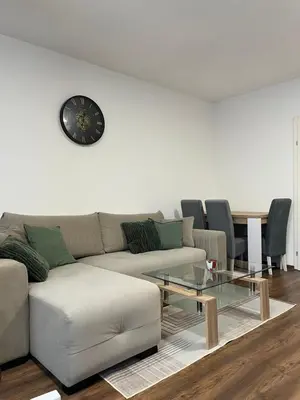 a living room with a couch and a clock on the wall at TM Studio Apartment Prijedor in Prijedor