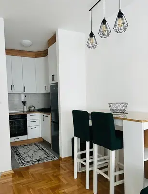 a kitchen with white cabinets and a table and chairs at Apartment Stepanova in Banja Luka