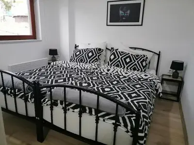a black and white bed in a white bedroom at Apartments EDEN in Vlasic
