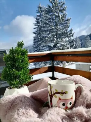 a coffee cup sitting on a blanket next to a pine tree at Apartments EDEN in Vlasic