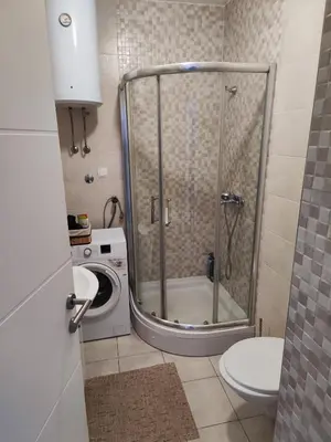a shower in a bathroom with a toilet and a washing machine at Dunja Doboj in Doboj