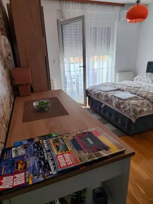 a bedroom with a bed and a table with a magazine at Dunja Doboj in Doboj