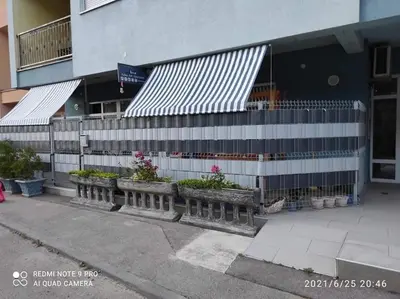 a building with potted plants in front of a building at Adna Art Apartment in Bihać