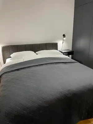 a bedroom with a large gray bed with a side table at Apartment in the center with free parking in Banja Luka