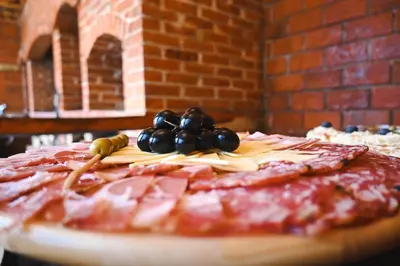 a pizza with meat and grapes on a table at Villa Fluviale in Jezero